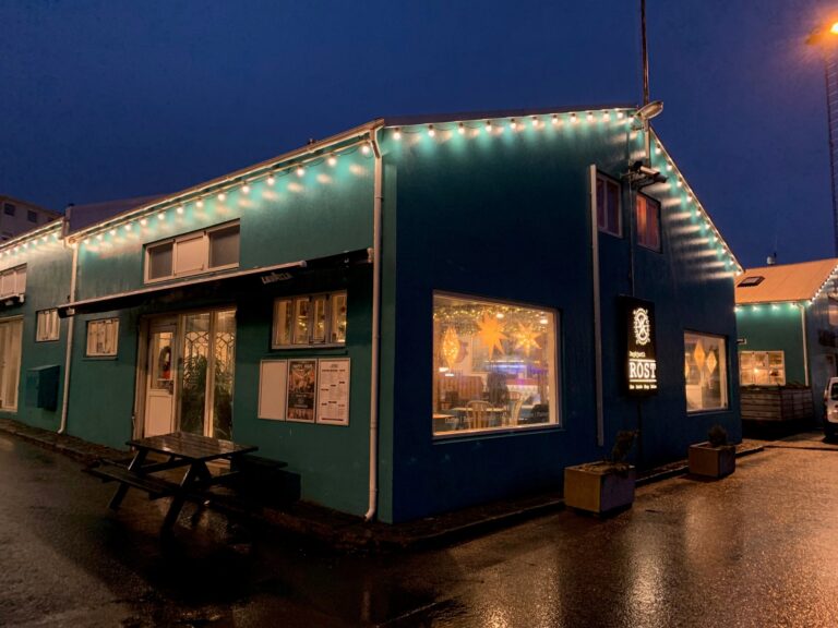 Teal building at night with string lights and signage