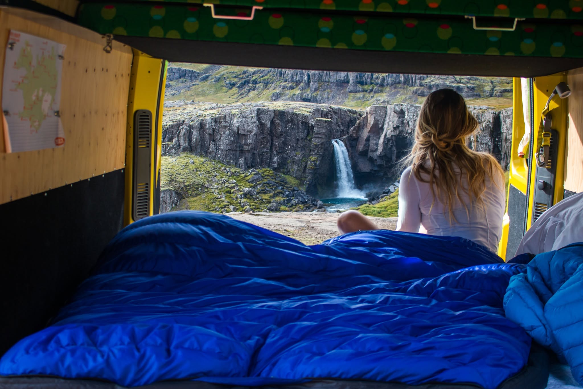 Woman sits in a van overlooking a waterfall