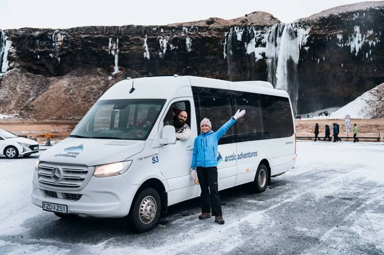 Woman waving by a white Arctic Adventures tour van