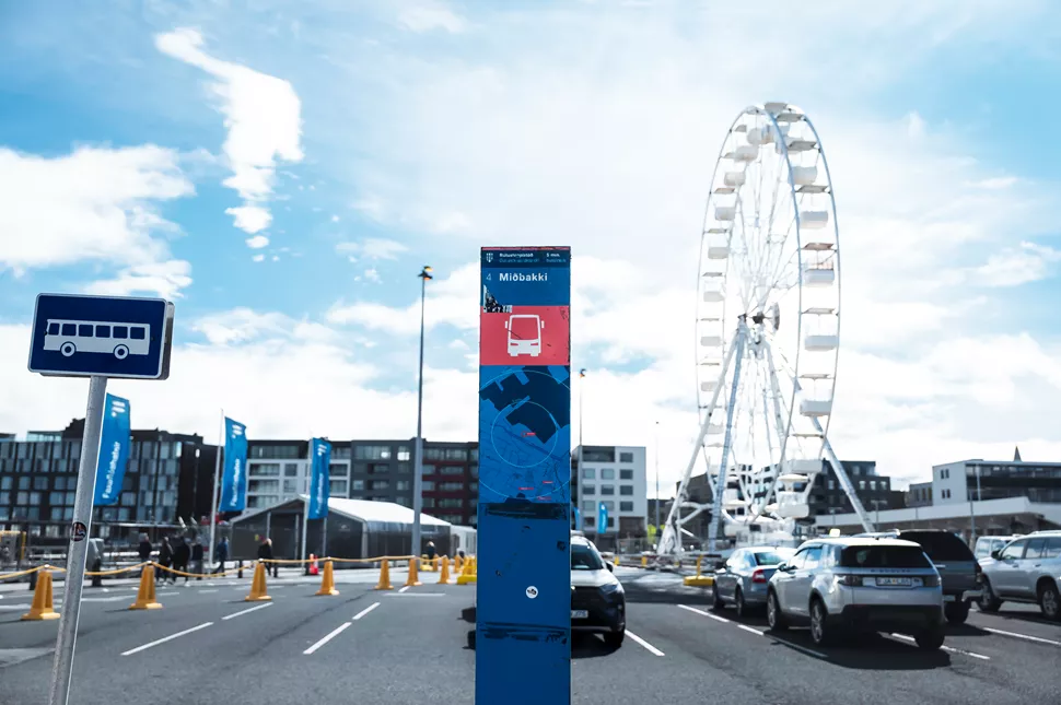 A bus stop sign with a ferris wheel background