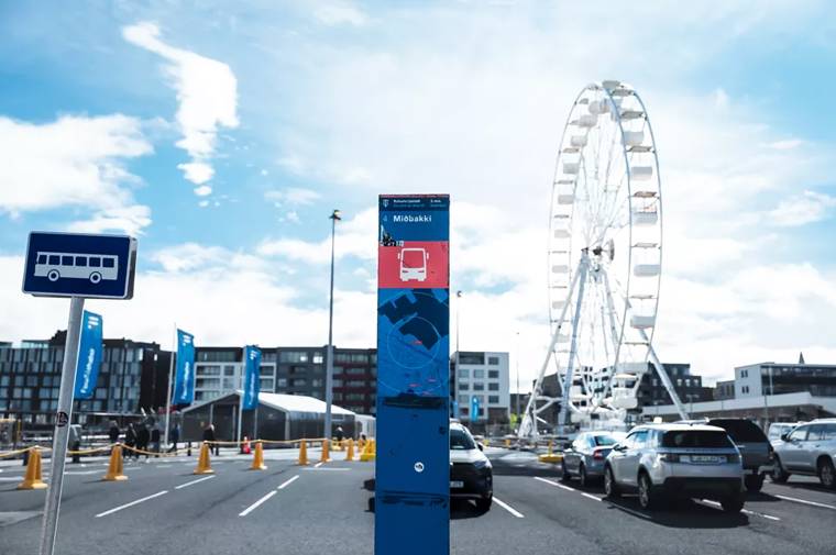 Bus stop sign in front of a Ferris wheel