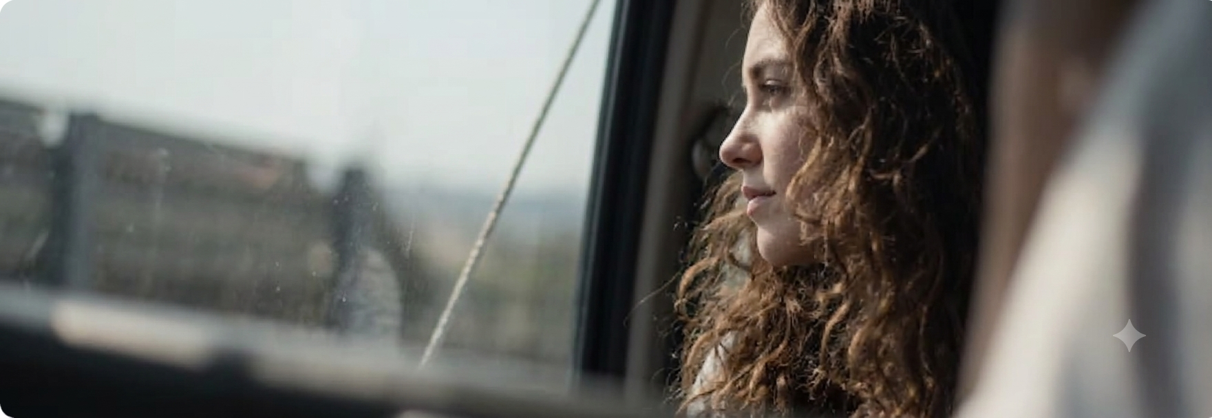 Woman with curly hair looking out car window