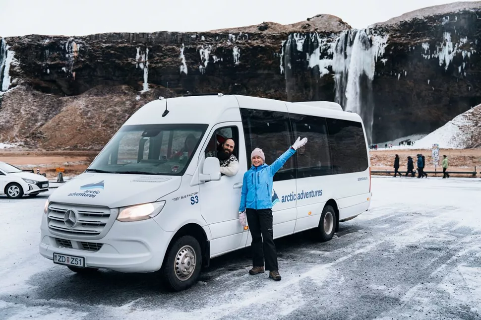 A woman posing beside an Arctic Adventures tour van